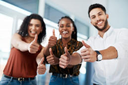 A group of three business people giving a thumbs up
